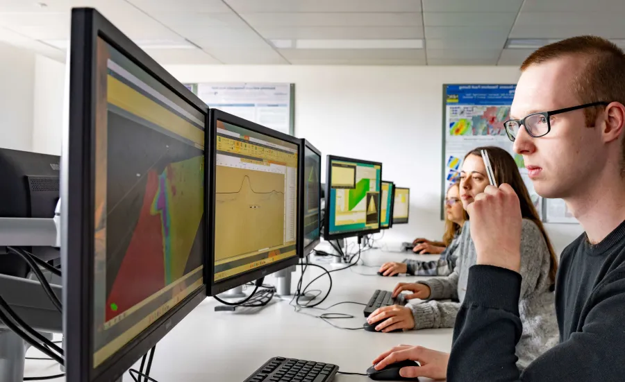 Environmental Geoscience students sitting in a computer lab looking at colourful graphs and survey results on screens.