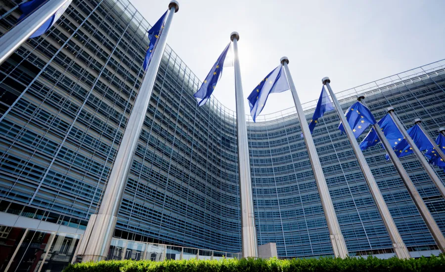 European parliament building with EU flags flying outside.
