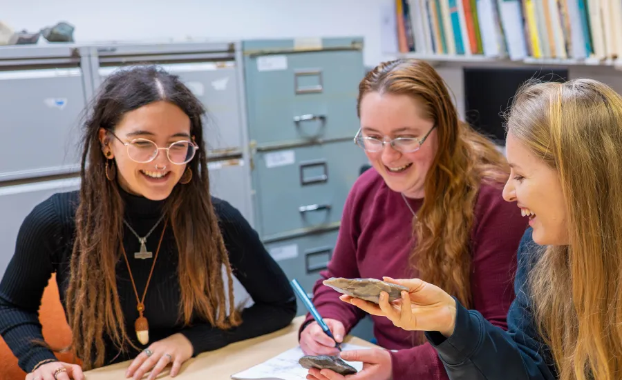 A group of Maritime Archaeology masters’ students sitting around a table examining flint arrow heads.