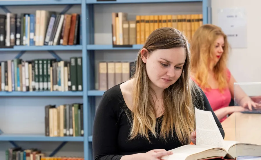 Nineteenth century literacy students studying books in the library.