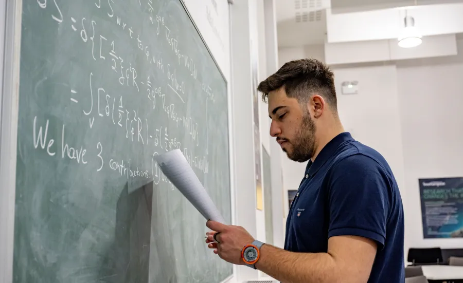 picture of someone writing a maths equation on a blackboard