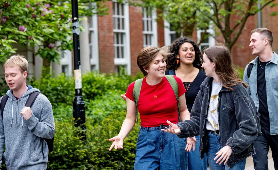 A group of modern language students laughing and chatting as they walk along Avenue Campus.