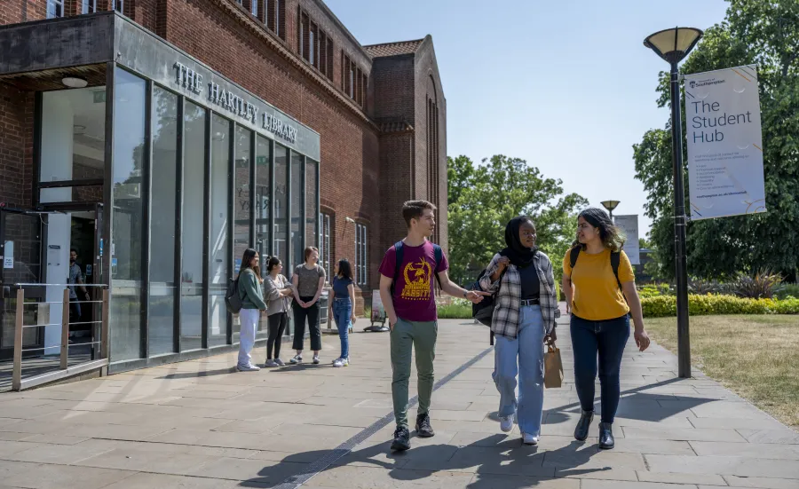 Three students walking past the Hartley Library