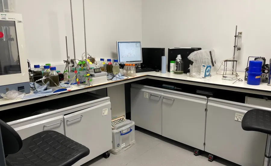 Workspace at the environmental laboratory with scientific equipment, bottles, a computer showing a graph, and digital scale.
