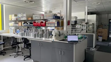 A view of the Environmental laboratory with workbenches, shelves filled with supplies, and a laptop open on a table.