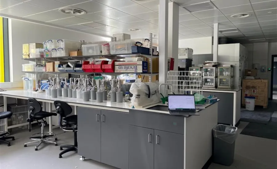 A view of the Environmental laboratory with workbenches, shelves filled with supplies, and a laptop open on a table.