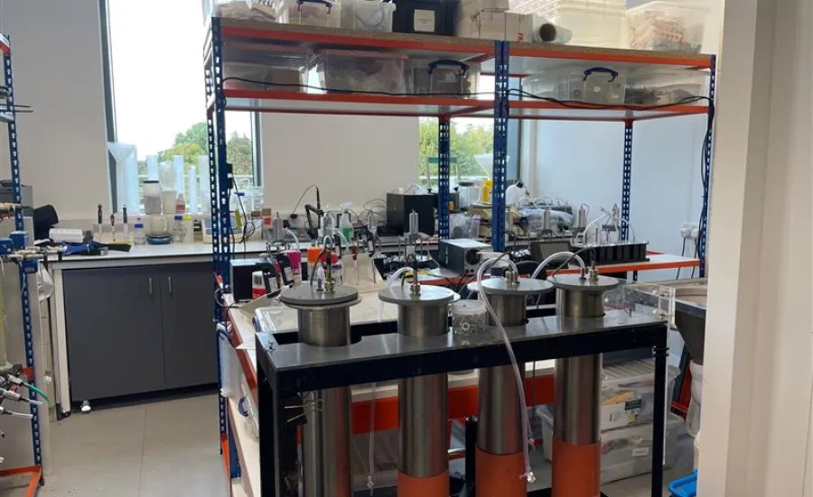 One of the rooms at the environmental laboratory with equipment, shelves, and a trolley with metallic cylinders.