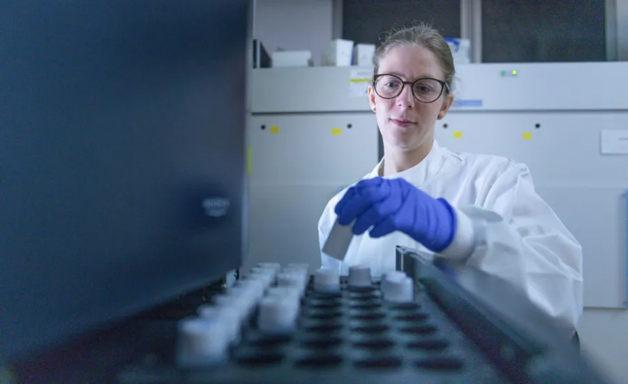 Person in a lab coat and blue gloves loading 300SL