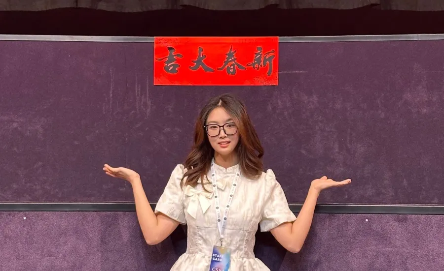 Shuheng Zhand standing in front of a banner in Chinese