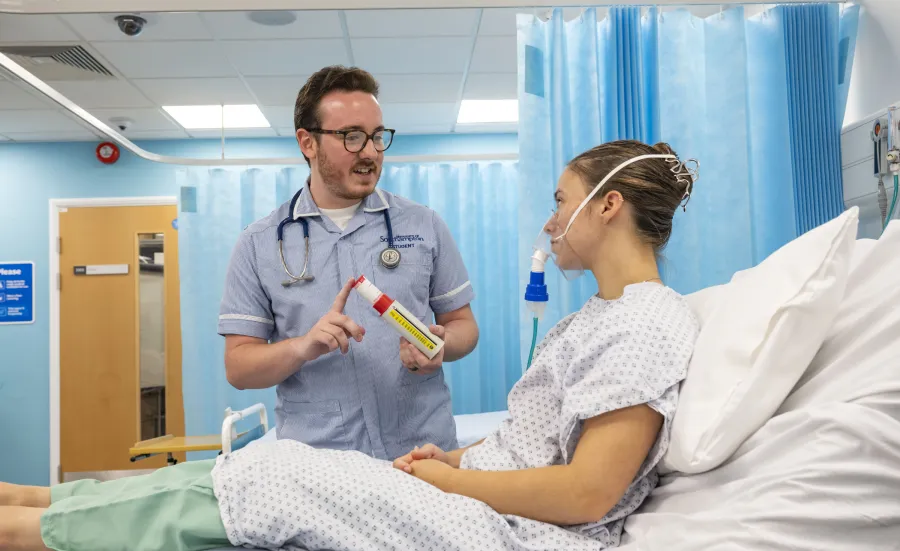 Student nurse helping patient with breathing equipment