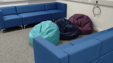 An empty room with sofas, beanbags, and a TV mounted on the wall.