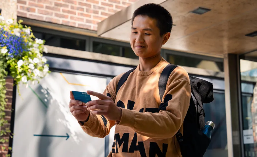 A student holding their ID card while stood outside the entrance to University of Southampton's Student Hub.