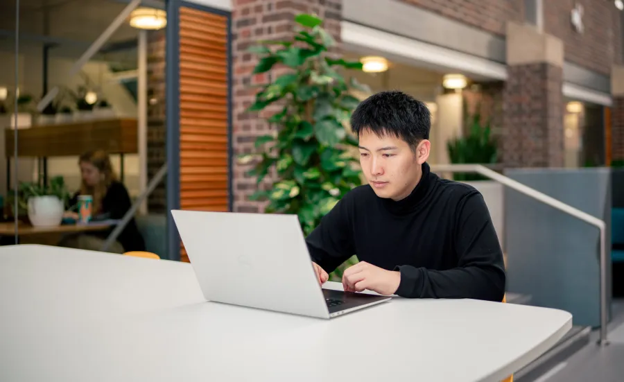 A student sat at a desk in the University of Southampton's Student Hub, with a laptop open on the desk.