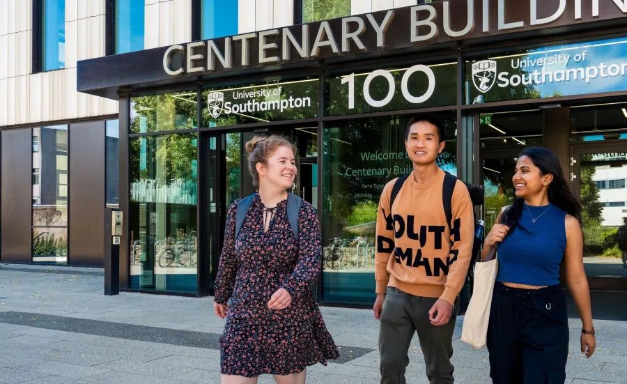 Three students walking outside the entrance to Centenary Building, also known as Building 100, on the University of Southampton's Highfield campus.