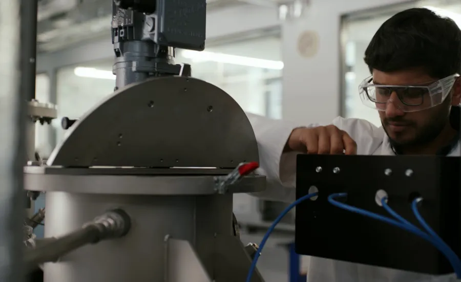Advanced chemical engineering student in safety goggles operating chemical engineering equipment in a laboratory.
