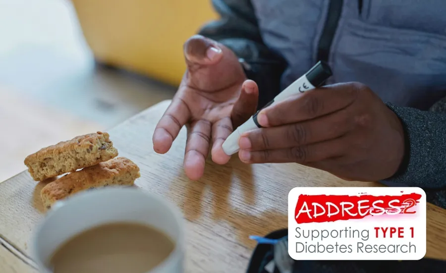 Person using a glucose meter on their fingertip beside a cup of coffee and biscotti on a table.