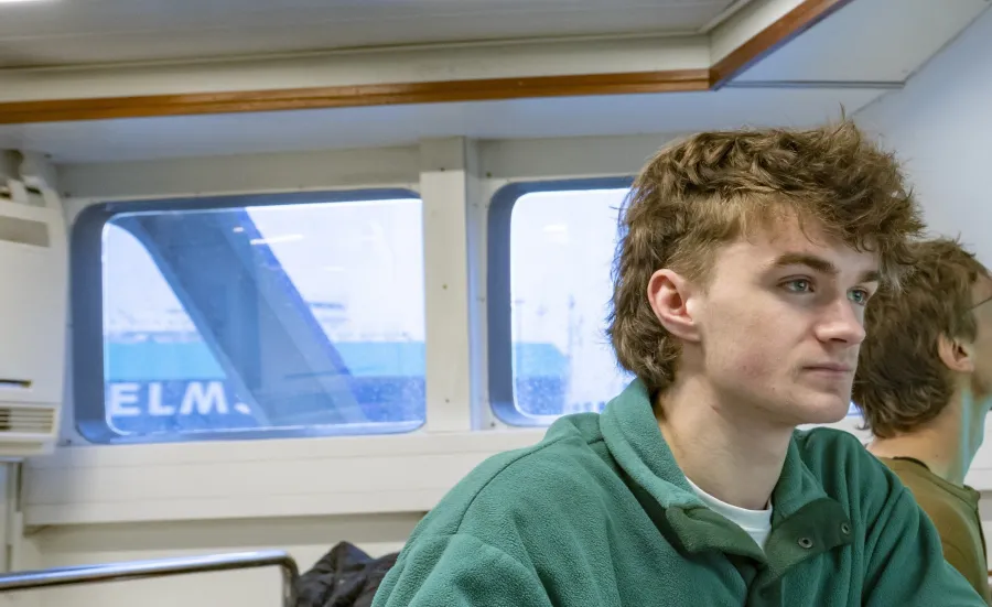 Students on the research vessel looking at screens showing colour-coded visual data of seabed mapping.