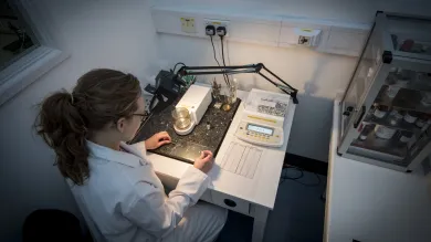 Person in a lab coat working with a digital scale in a laboratory.