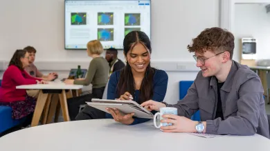 Two students using a tablet in a University study space.