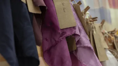 Different purple fabrics on a rack in a textiles studio