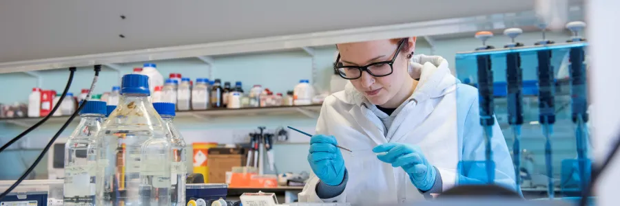 A researcher in a lab, examining a slide