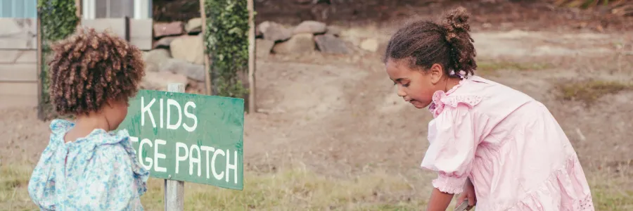 Two children gardening at a kids' veggie patch.