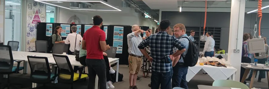 Modern office space with several people engaged in conversation around a table filled with refreshments. 