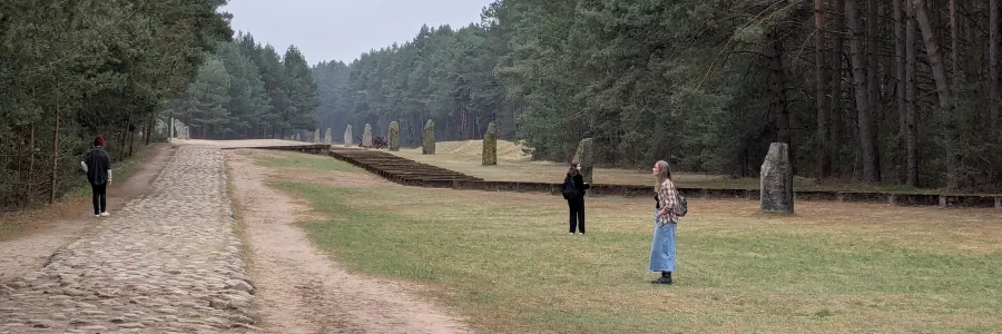 Individuals are shown walking on grass along a tree lined path