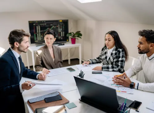 Group of 4 people talking around a work table