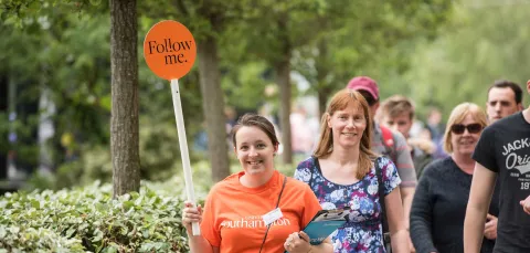 A student leads visitors on a tour of campus at an open day.