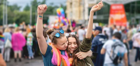 2 ladies hugging at a gay pride parade.