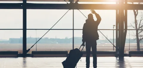 International student waving goodbye at the airport.