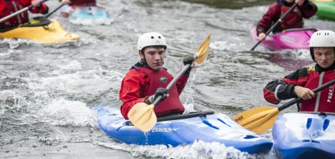 Students in canoes navigating a small rapids. 