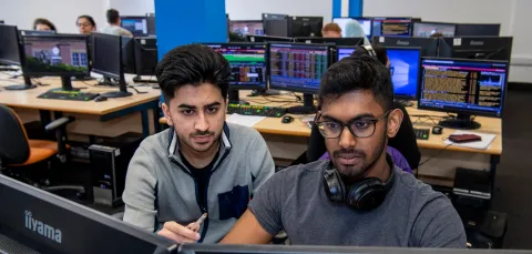 Student and tutor looking at business trading screen.