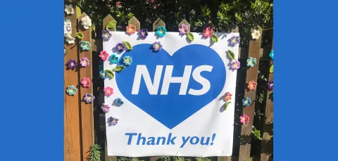 Thank you NHS sign decorated with flowers on garden gate.