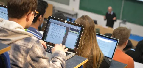 Students in lecture theatre writing notes on laptops