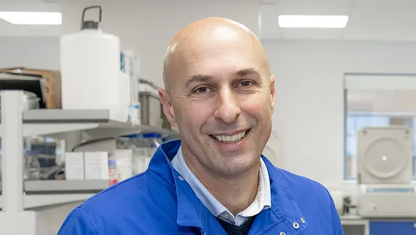 Dr Stephen Beers, wears blue protective gear in a laboratory
