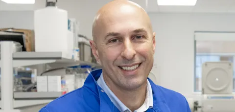 Dr Stephen Beers, wears blue protective gear in a laboratory