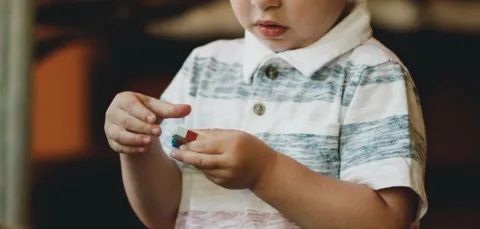 A child is absorbed in playing with brightly coloured building bricks