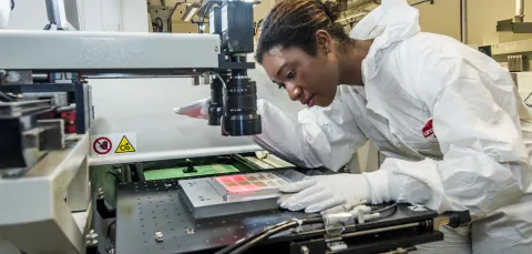 A student wearing protective clothing uses printed electronics and materials equipment