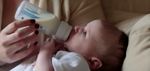 A mother feeds her baby from a bottle