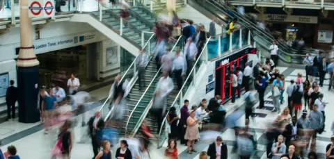 Many people in train station with stairs.