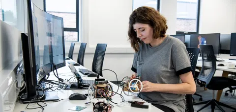 A researcher at a desk with computers and electronic equipment