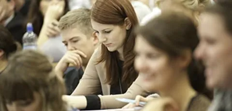 A postgraduate researcher concentrating on her notes during a seminar.