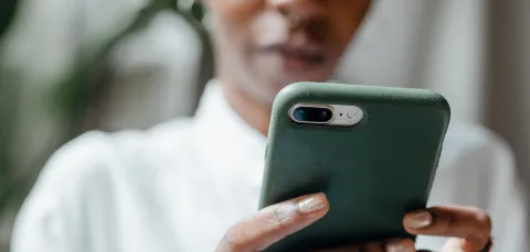 Pexels image of a person clasping a mobile phone intently looking at screen