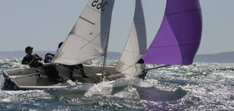 Two sailors in a small boat in rough waters