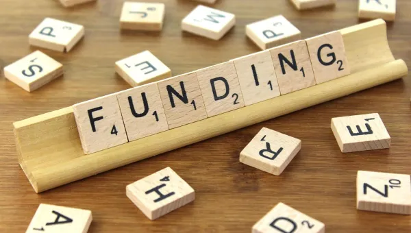 Wooden tiles from a game spelling out the word funding