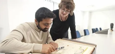 Staff looking at maps from the library archive