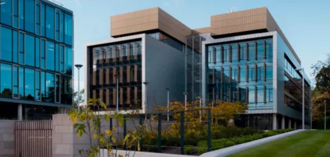Building 175 on Boldrewood Innovation Campus, a large modern glass and concrete building with lawns and plants to the front