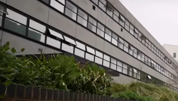 Close-up of a long, 3 storey concrete and glass building